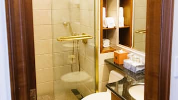 Ein Hotelbad mit einer Duschkabine, einer weißen Toilette und einem Waschtisch mit Spiegel und Ablageflächen.