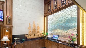 Mostrador de recepción con una computadora portátil, un teléfono y una planta decorativa.