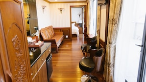 Habitación de hotel con piso de madera, un sofá, una silla, un armario y un espejo.