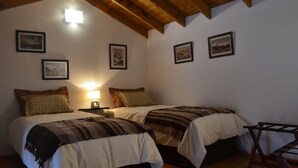 Ein Schlafzimmer mit zwei Betten, Holzbalken an der Decke und gerahmten Bildern an den Wänden.