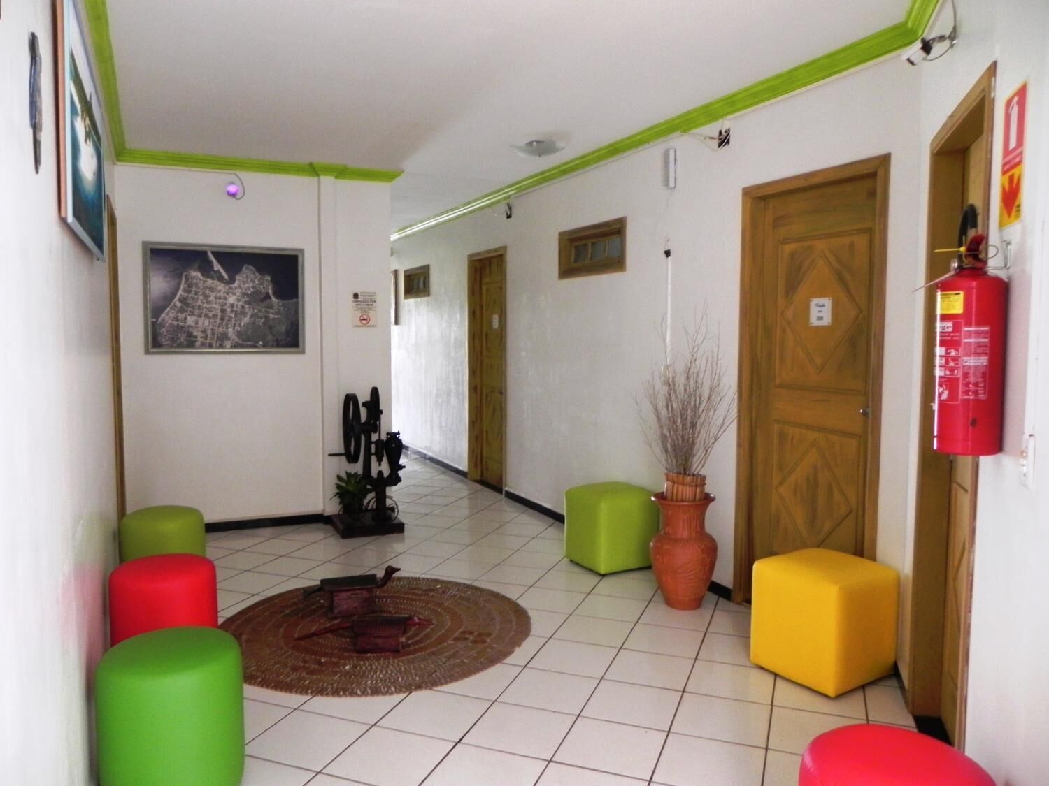 A lobby with a tiled floor, green and yellow seating, a fire extinguisher, and a framed picture on the wall.