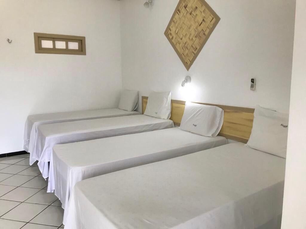 A room with three single beds, each with a wooden headboard and white bedding.