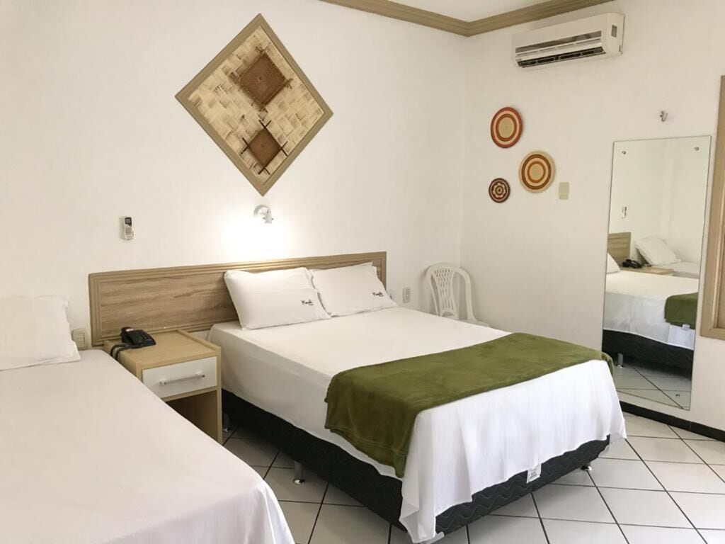 A hotel room with a bed, a nightstand, a chair, and a mirror.