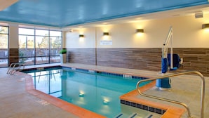 An indoor swimming pool with a lifeguard station, a no lifeguard on duty sign, and a view of the outside patio area. - Fairfield Inn & Suites by Marriott Flagstaff Northeast (Flagstaff)