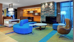 A modern hotel lobby with a stone fireplace, blue seating, and a reception desk. - Fairfield Inn & Suites by Marriott Flagstaff Northeast (Flagstaff)