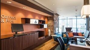 A reception area with a wooden desk, a computer, a television, and a seating area with a sofa and chairs. - Fairfield Inn & Suites by Marriott Flagstaff Northeast (Flagstaff)