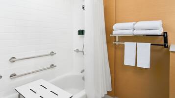 Un baño moderno con una bañera blanca, una cortina de ducha y un perchero con toallas dobladas.