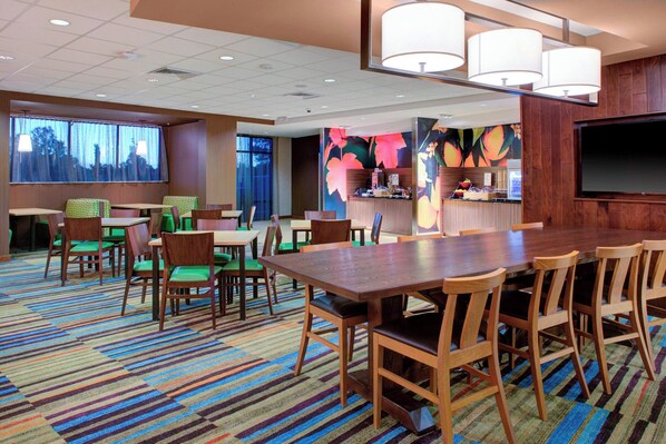A hotel conference room with a large table, chairs, and a TV screen.