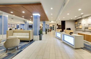 A modern hotel lobby with a reception desk, seating area, and a dining area. - Holiday Inn Express & Suites Dallas NW - Farmers Branch by IHG (Farmers Branch)