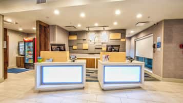 A hotel reception area with two reception desks, a Coca-Cola refrigerator, and a vending machine.