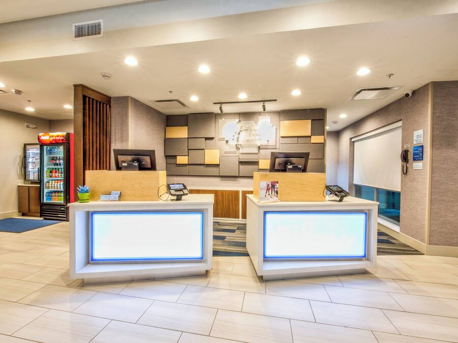 A hotel reception area with two reception desks, a Coca-Cola refrigerator, and a vending machine.