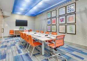 A conference room with a long table, orange chairs, a flat-screen TV, and framed artwork on the walls. - Holiday Inn Express & Suites Dallas NW - Farmers Branch by IHG (Farmers Branch)
