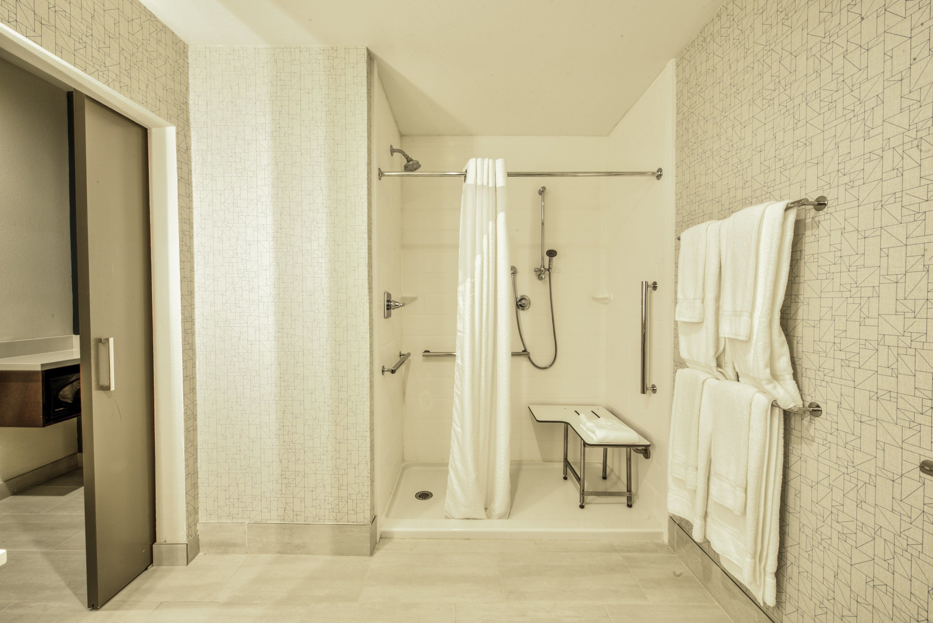 A modern bathroom with a shower, a toilet, and a towel rack.
