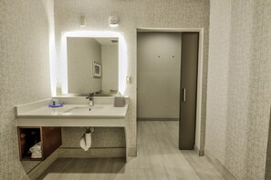 A modern bathroom with a large mirror, white sink, and a towel rack. - Holiday Inn Express & Suites Dallas NW - Farmers Branch by IHG (Farmers Branch)
