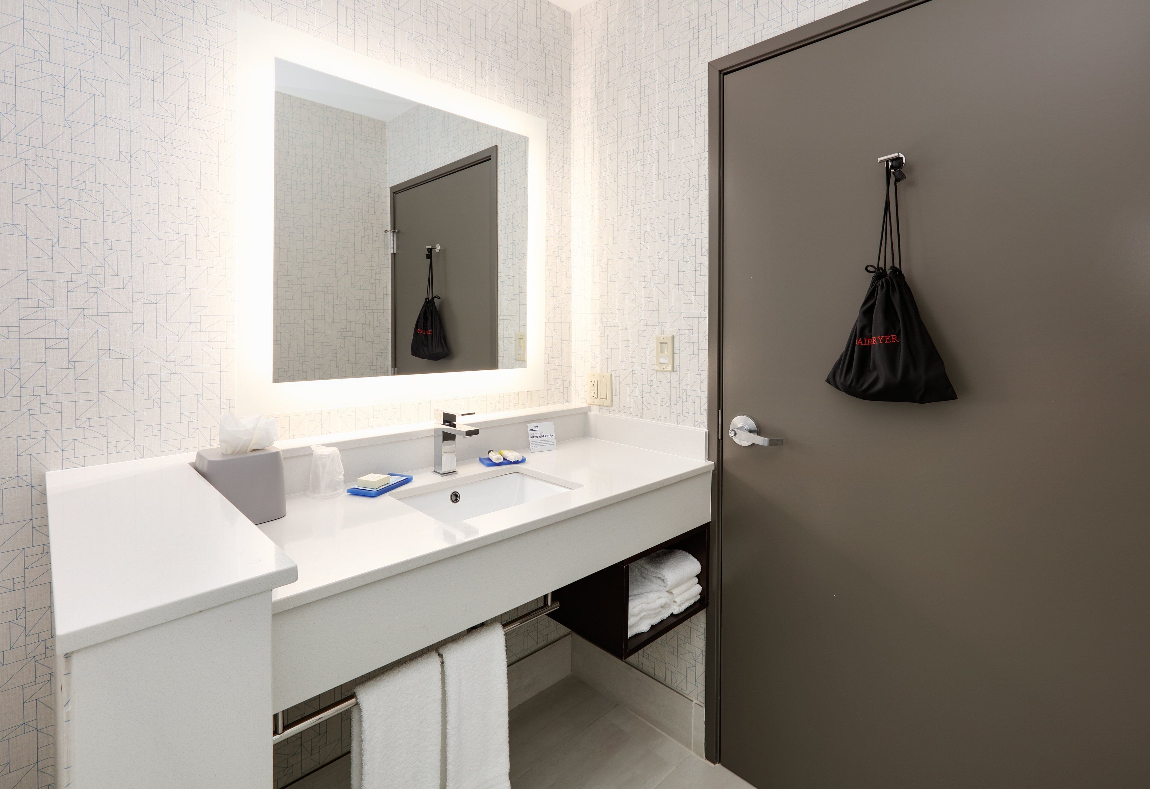 Une salle de bain moderne avec un lavabo blanc, un grand miroir et un porte-serviettes.
