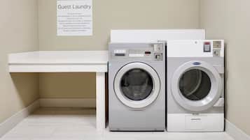 A guest laundry area with two front-loading washing machines, a white counter, and a sign with laundry instructions.