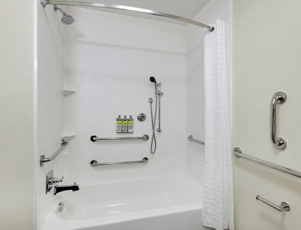 Un baño con bañera, ducha, barras de apoyo y un perchero para toallas.