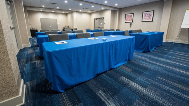 A conference room with multiple tables covered in blue tablecloths, arranged in rows. - Holiday Inn Express & Suites Lake Charles South Casino Area by IHG (Lake Charles)