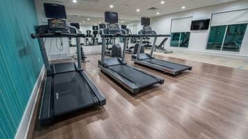 A gym with treadmills, exercise equipment, and mirrors.