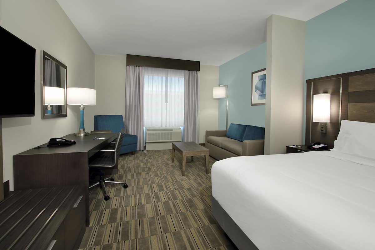 A hotel room with a bed, desk, chair, and a television.