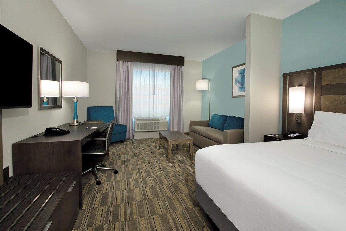 A hotel room with a bed, desk, chair, and a television.