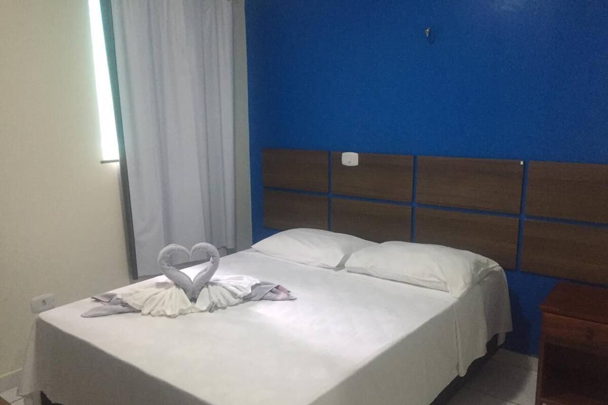 A hotel room with a bed, a headboard, and a nightstand.