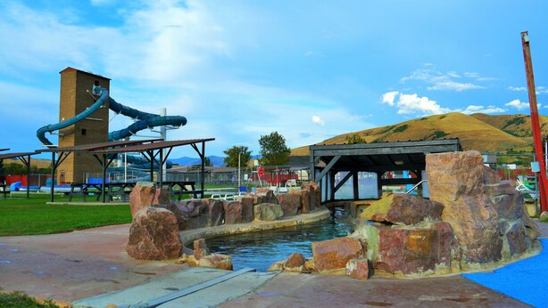 A water park with a water slide, a pool, and a rock formation.