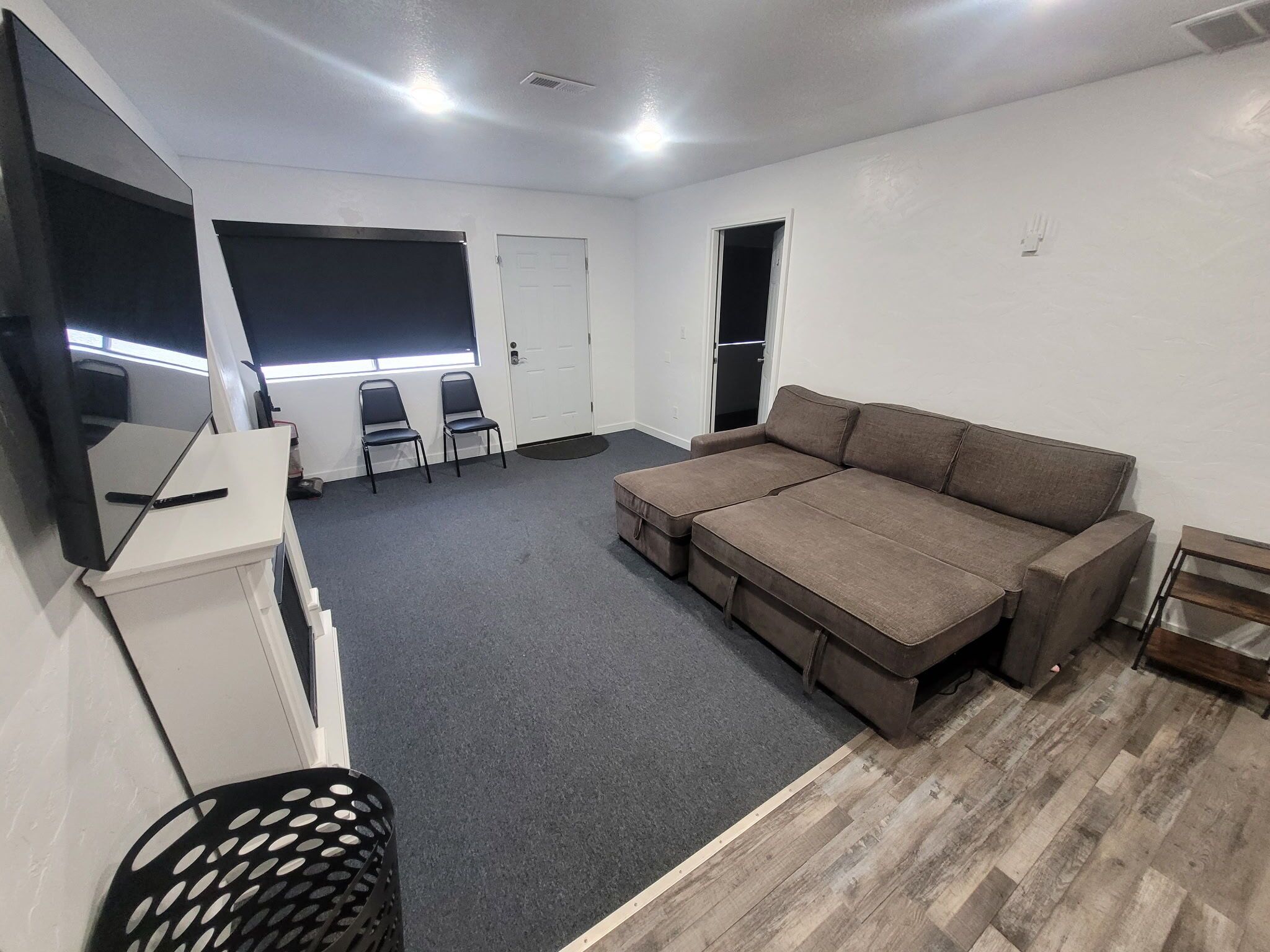Una habitación con sofá, sillas, televisor y una puerta.