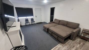 Una habitación con sofá, sillas, televisor y una puerta.