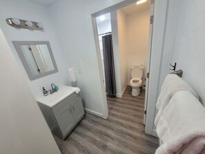 Un baño con lavamanos, espejo e inodoro.