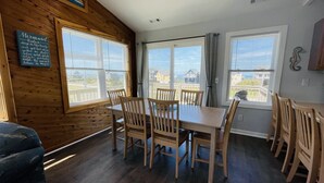A dining area with wooden furniture and large windows. - Hatteras Hideaway 3 Bedroom Cottage by RedAwning (Frisco)