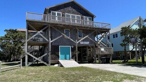 A two-story building with a balcony, a door, and a sign that reads 'Hatteras Golf Course.' - Hatteras Hideaway 3 Bedroom Cottage by RedAwning (Frisco)