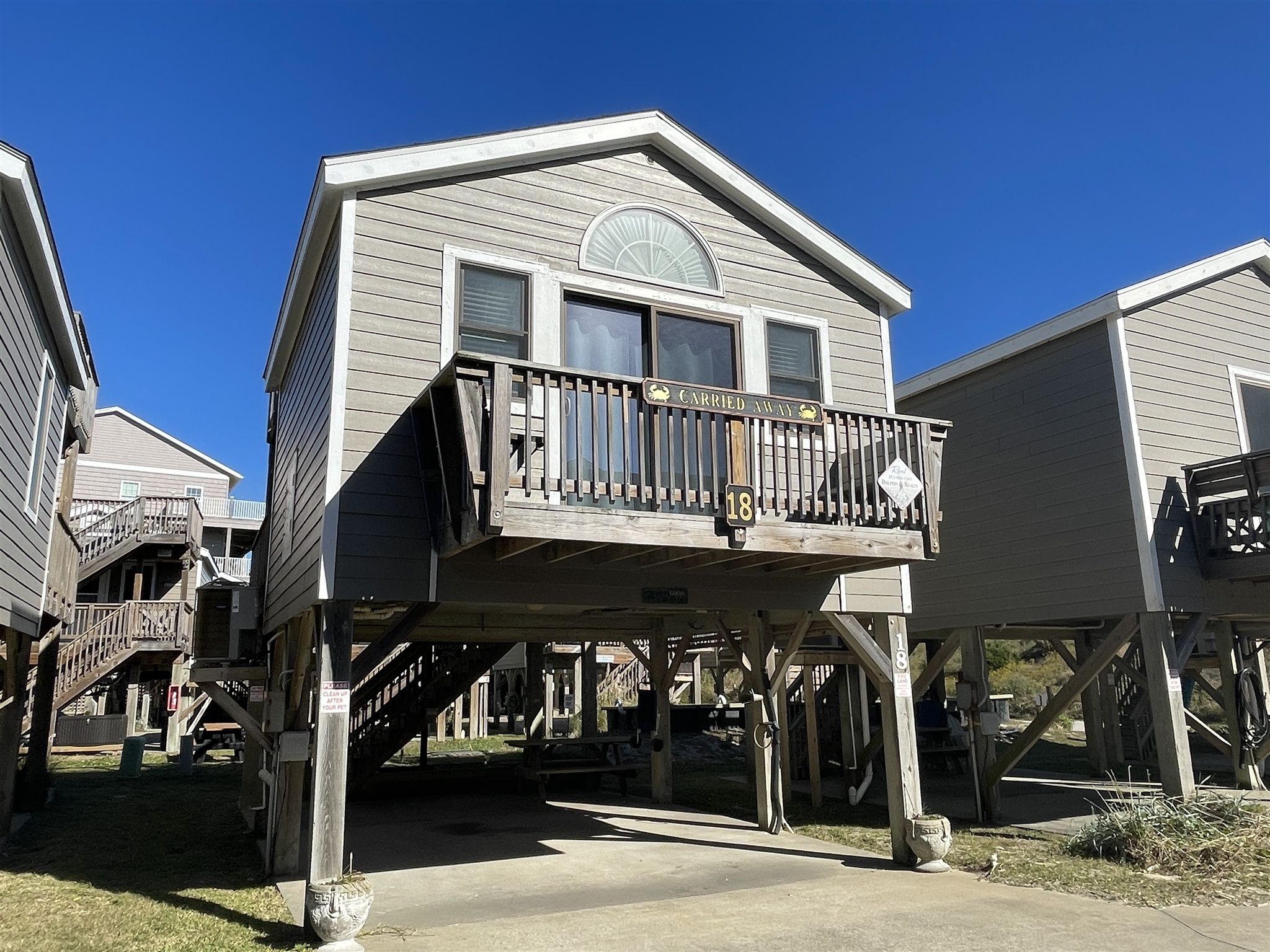 A two-story wooden cabin with a balcony, a covered porch, and a small deck area.