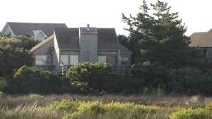 Een twee verdiepingen tellend huis met een gevel van natuursteen, een zichtbare schoorsteen en een veranda.