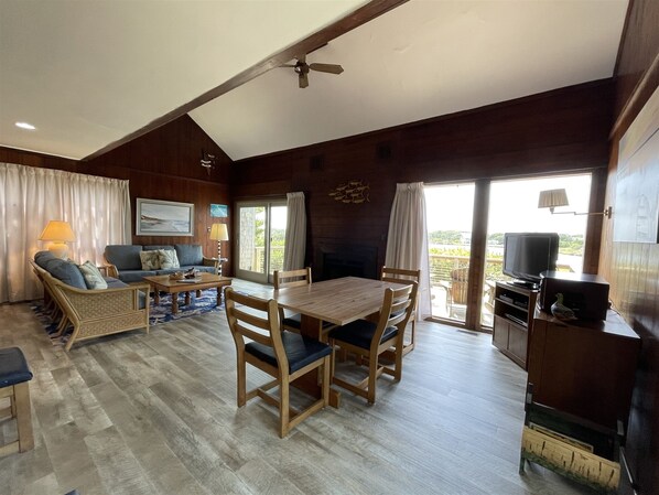 A cozy living room with a wooden dining table, chairs, a sofa, and a television.