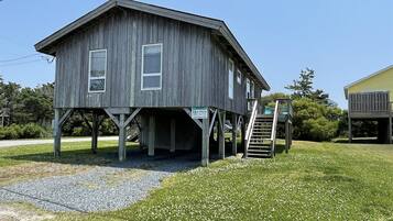A wooden house with a porch and a staircase leading up to it.