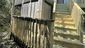 Een houten trap die leidt naar een terras met een balustrade.