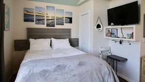 A bedroom with a bed, a TV, and wall art. - 4 Carolina Lady Studio Bedroom Condo by RedAwning (Hatteras)