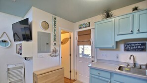 A kitchen with light blue cabinets, a stainless steel sink, and a wall-mounted clock. - 4 Carolina Lady Studio Bedroom Condo by RedAwning (Hatteras)