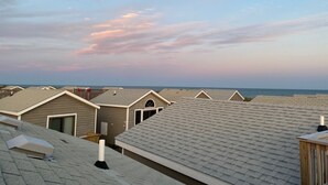 A row of beach cottages with sloped roofs, a wooden deck, and a view of the ocean.