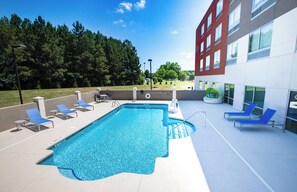 A swimming pool with lounge chairs and a building in the background.