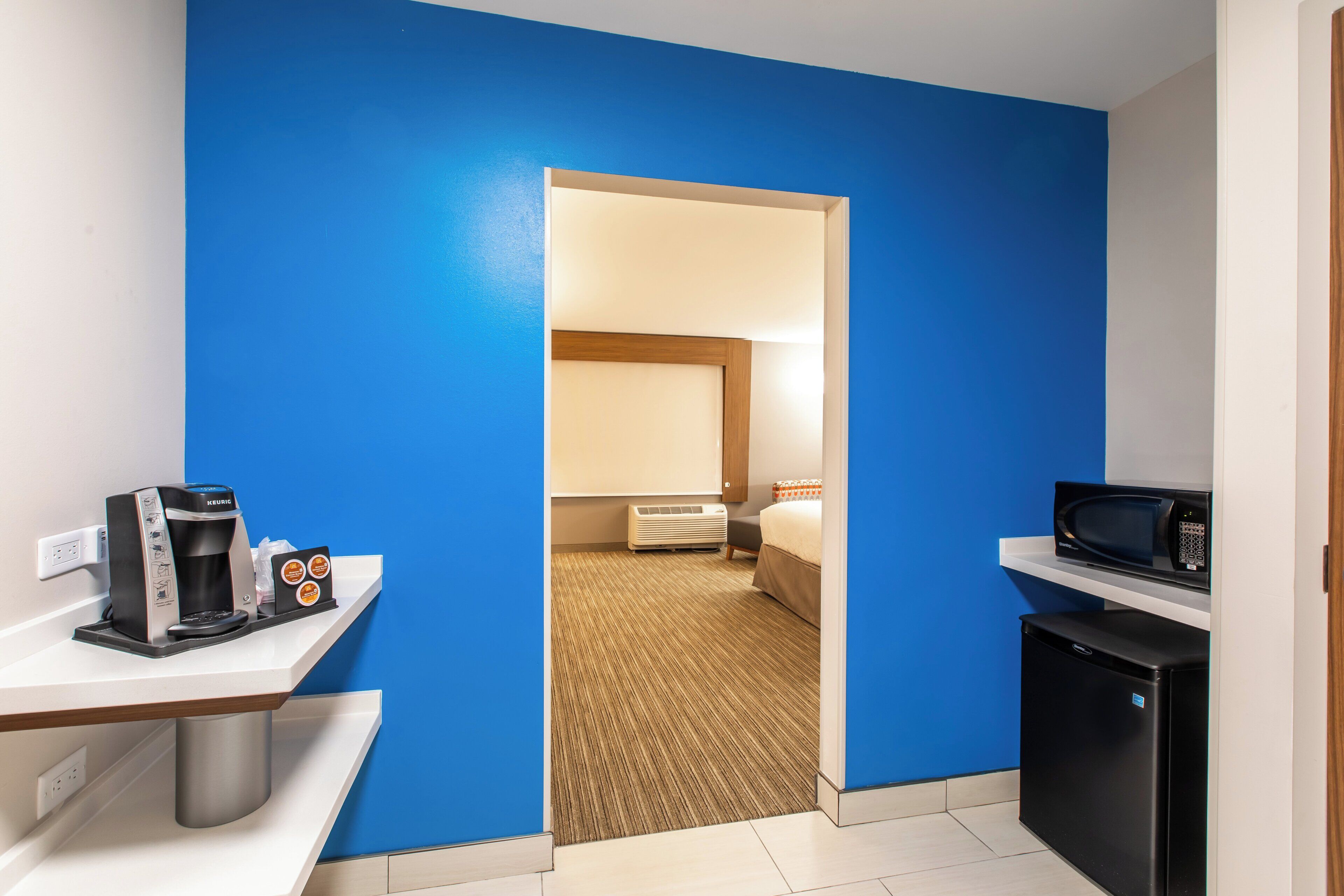 Ein Hotelzimmer mit einer Küchenzeile, einem Bett und einem Badezimmer.