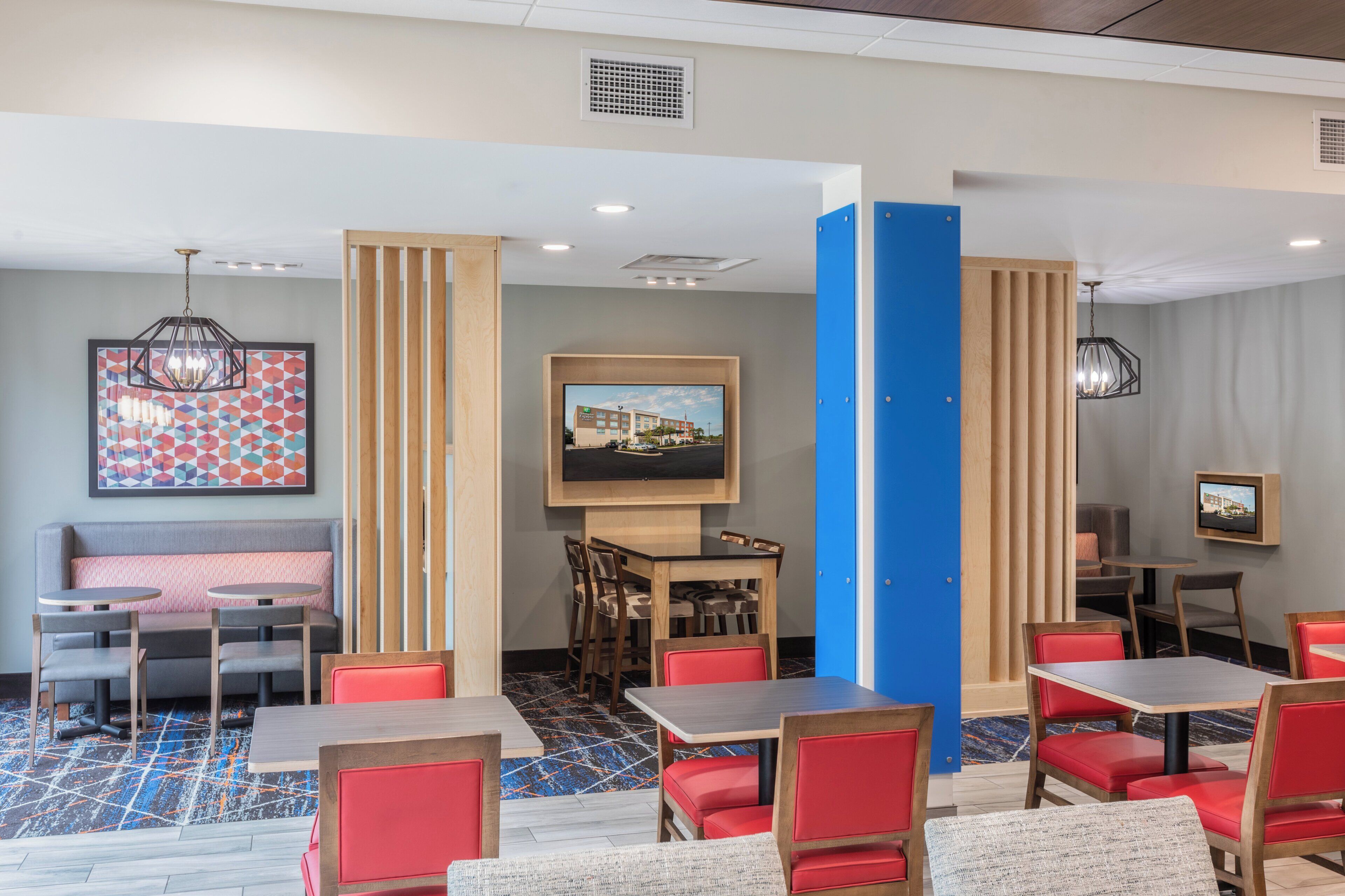 Un vestíbulo de hotel con una zona de estar, un área de comedor y una pantalla de televisión.