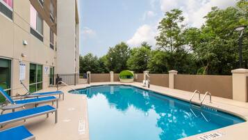 Relax by the pool surrounded by lush greenery and comfortable lounge chairs.
