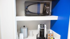 A kitchenette with a microwave, coffee maker, and coffee pods on a white countertop. - Holiday Inn Express & Suites Greenville S- Piedmont by IHG (Piedmont)