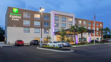 Een Holiday Inn Express & Suites hotel met een parkeerplaats en verschillende geparkeerde auto's voor het gebouw.