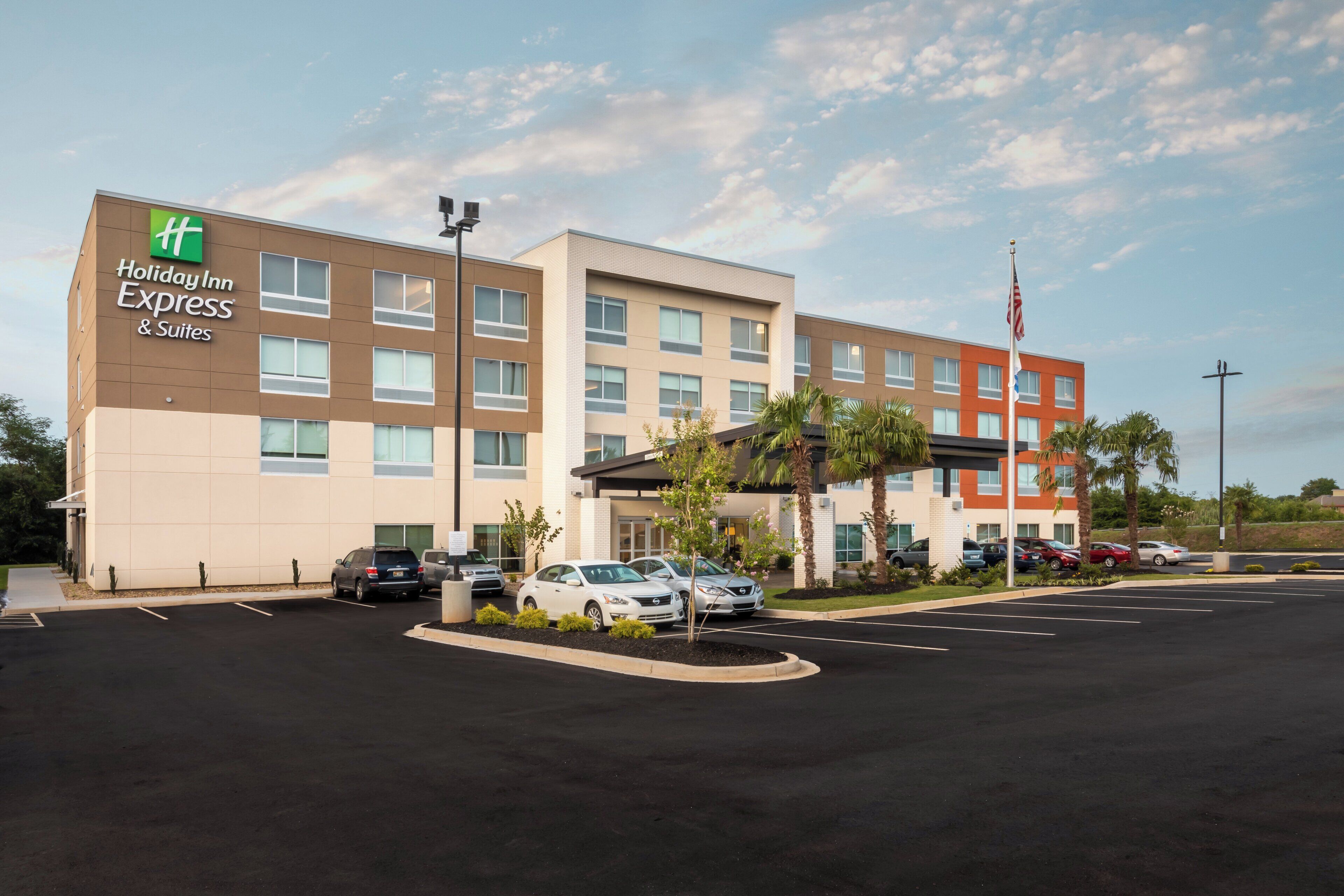 A Holiday Inn Express & Suites hotel with a parking lot and several cars parked in front.
