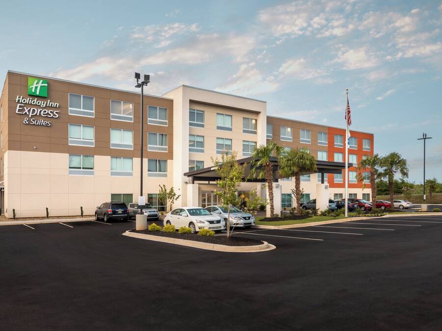 A Holiday Inn Express & Suites hotel with a parking lot and several cars parked in front.