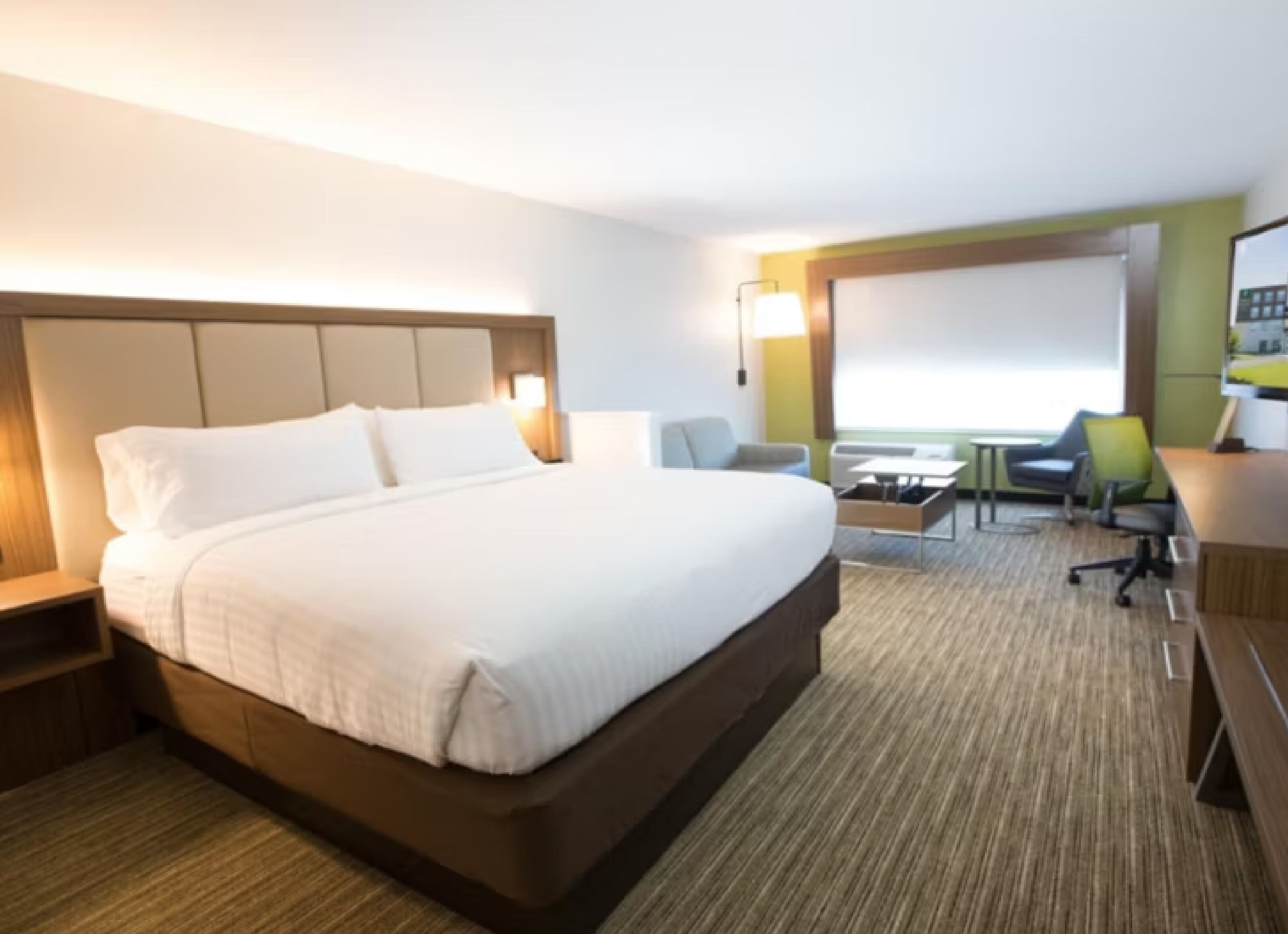 Una habitación de hotel con una cama grande, un escritorio, una silla y una mesita.