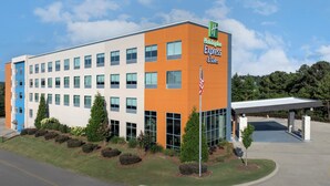 A Holiday Inn Express & Suites building with a modern design, featuring a flat roof, large windows, and a covered parking area.